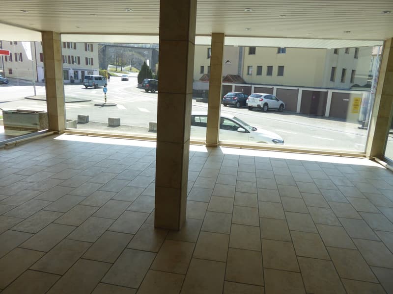 Empty entrance hall with large windows, concrete floor, column, cars in the street