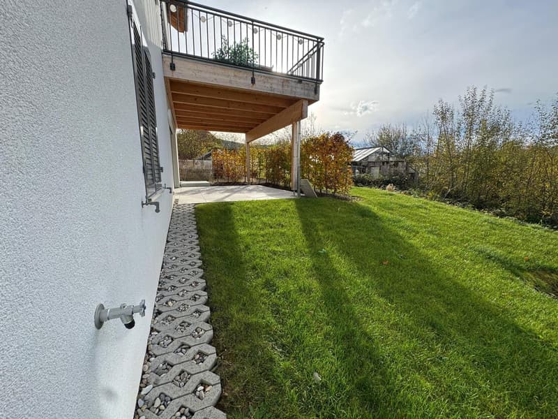 a well-maintained grassy yard with a wooden deck leading to a balcony