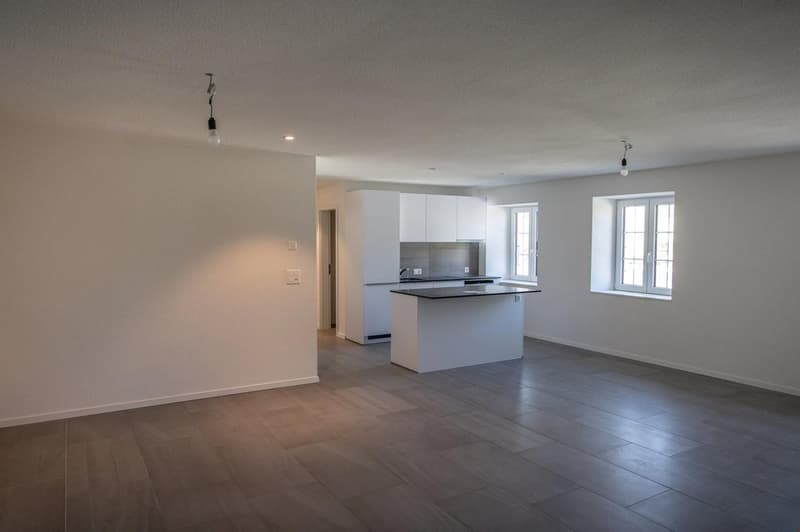 empty room with tiled flooring, white kitchen island, white cabinets, two windows, two hanging lights