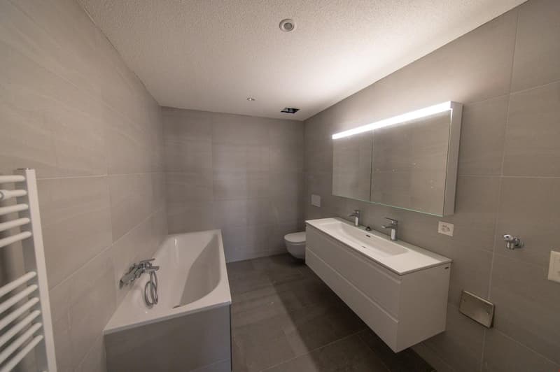 modern bathroom, white bathtub, white sink, white vanity, toilet, large mirror, towel rack