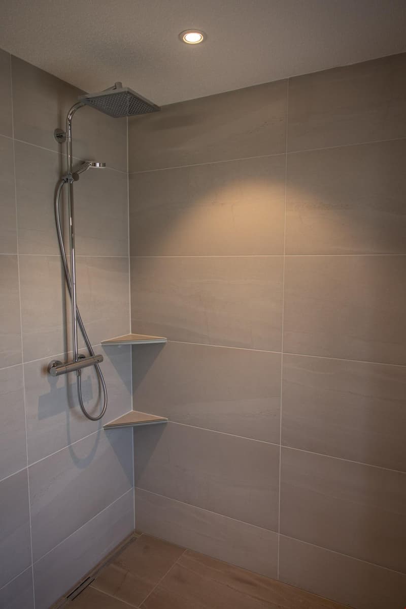 tiled walls, shower with shower head, two corner shelves