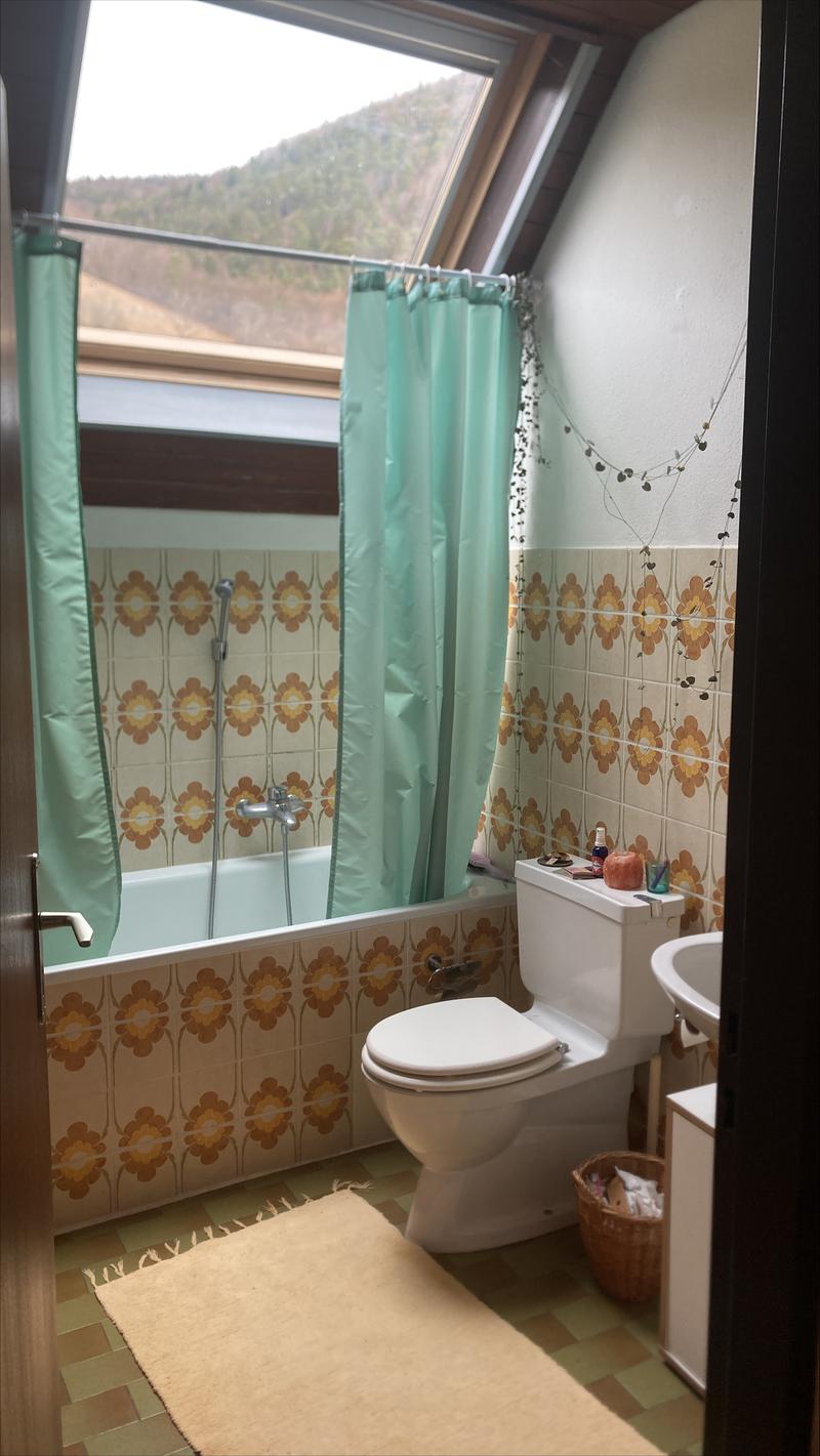 Bathroom with bathtub, toilet, sink, rug and tiled walls.