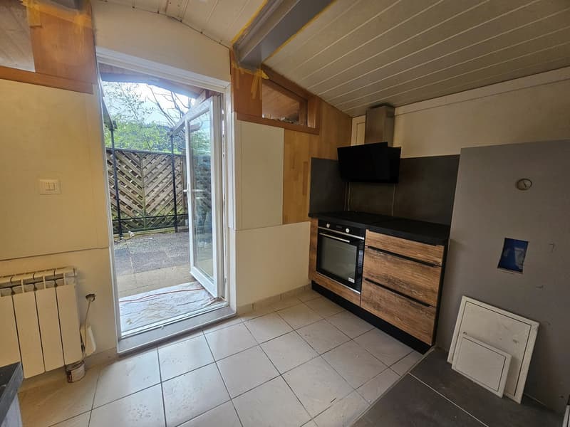 small kitchen with an oven, window and door leading to the outside