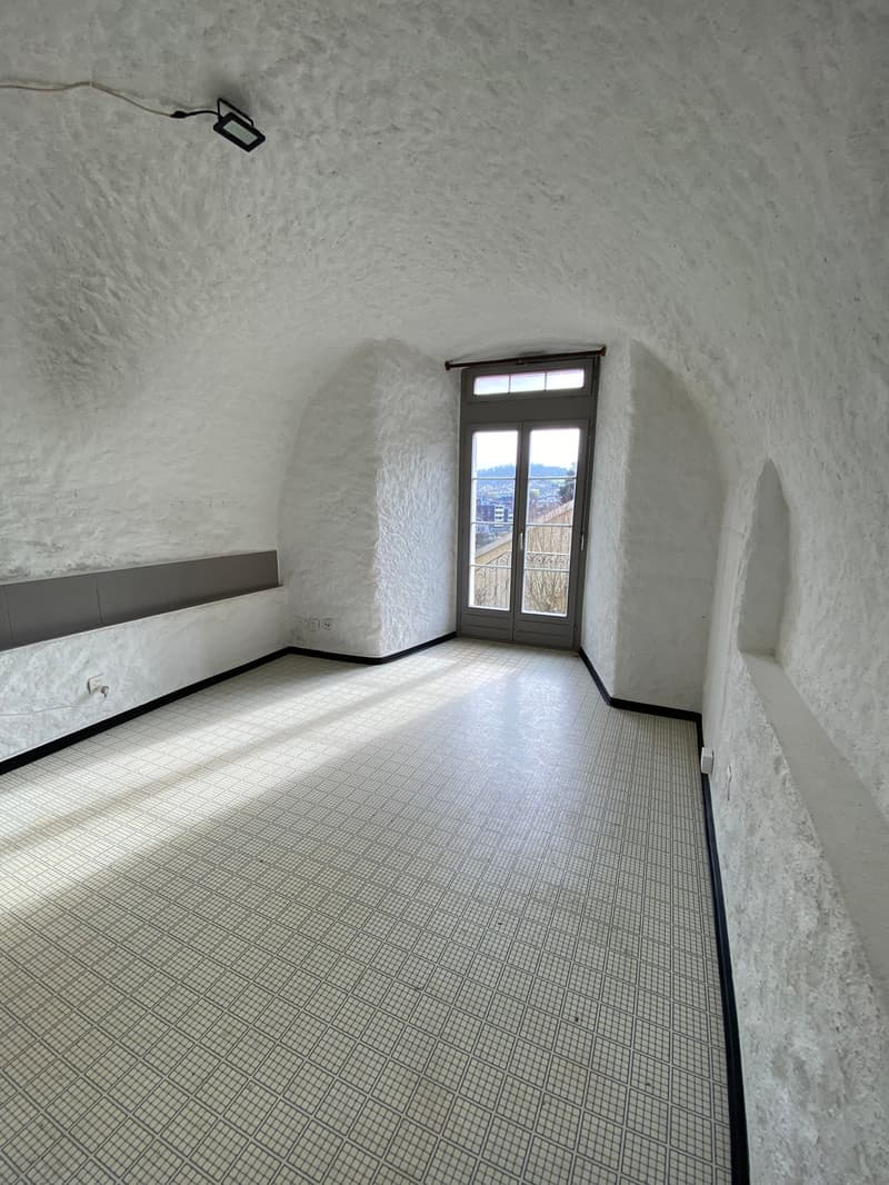 Empty room with white walls, tiled floor, and a glass door with a balcony view.