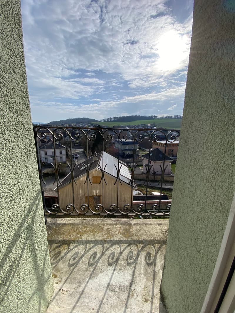 balcony with metal railing, view of houses and hills