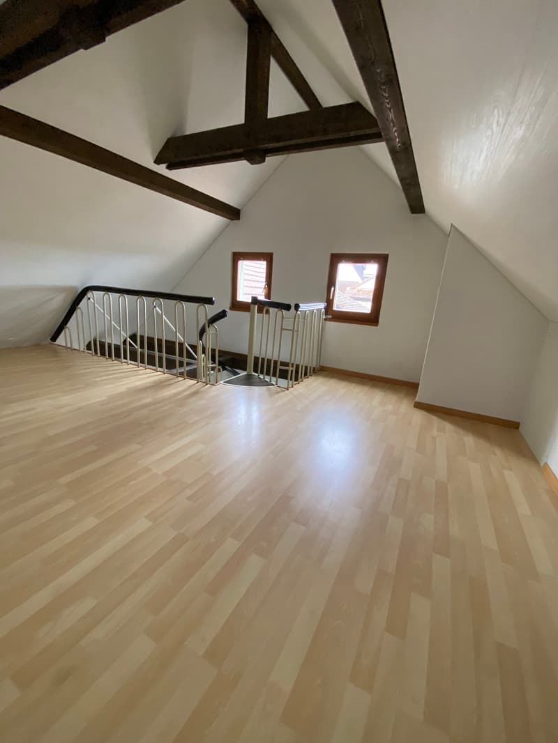 empty room, wooden floor, white walls, wooden beams, two windows, staircase