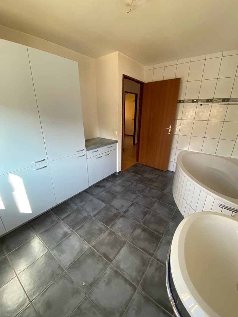 Bathroom with bathtub, sink, cabinets, and tiled floor