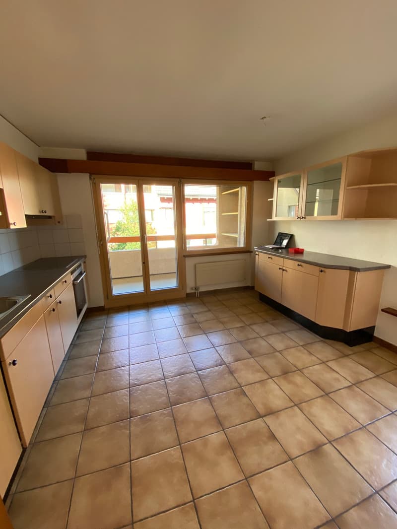 empty kitchen with tiled floor, cabinets, countertop, sink, sliding glass door to balcony