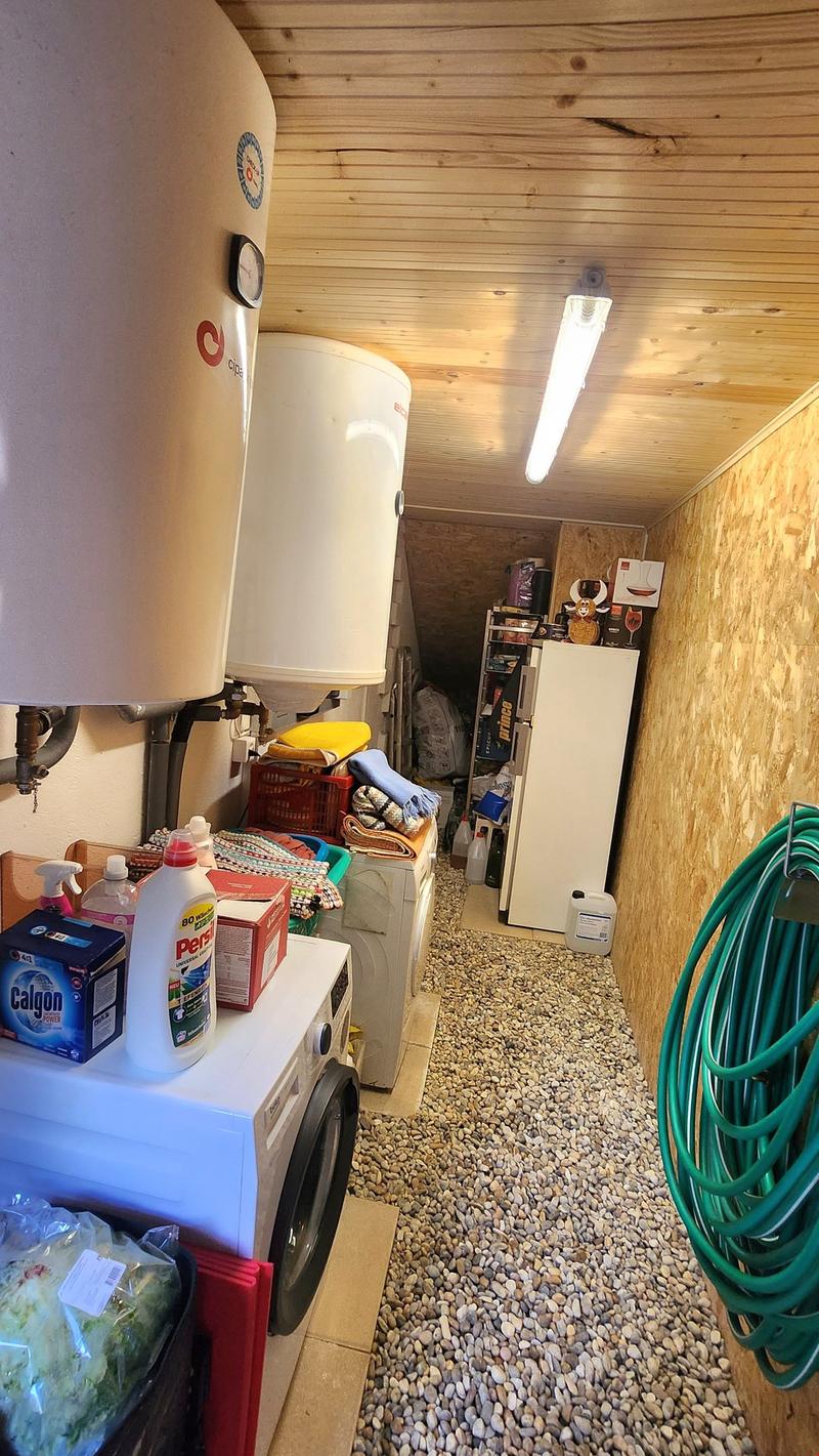 Laundry room with washing machine, dryer, water heaters, cleaning products, and storage boxes