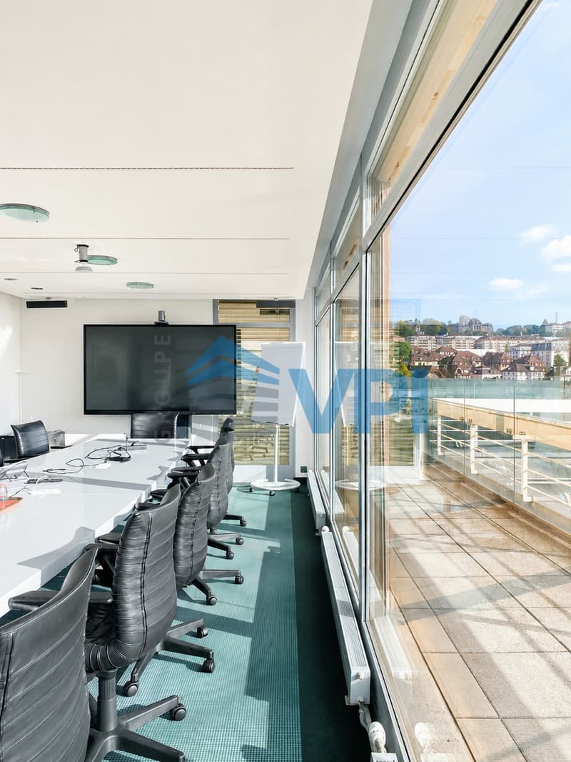 / a conference room with large windows overlooking the water and a conference table with chairs