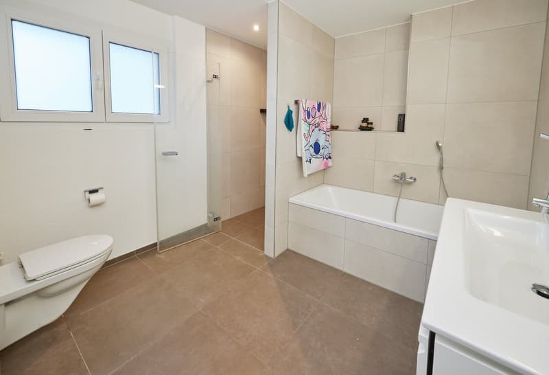 White ceramic tiles, modern fixtures, shower enclosure, bathtub, vanity with sink, toilet