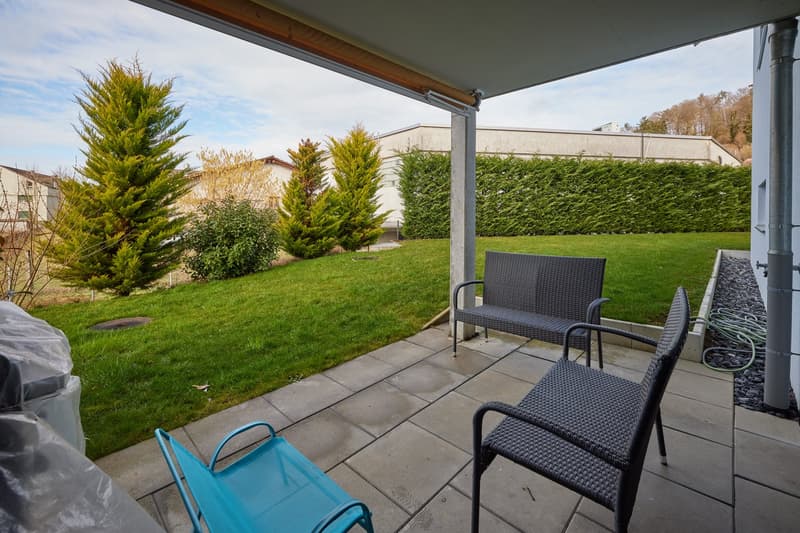 Covered terrace with seating, trees, and well-maintained grass lawn.