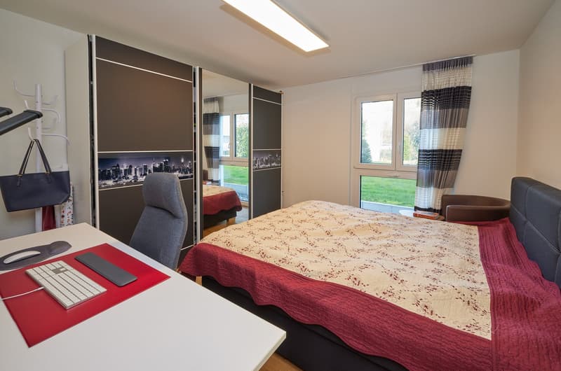 spacious bedroom with a bed, desk, and a closet