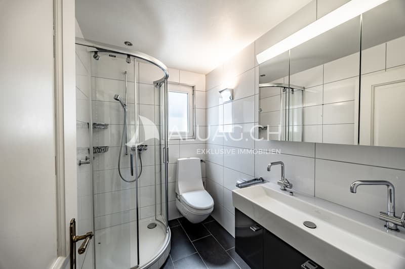 Modernes Bad mit Dusche, Doppellavabo und eleganten Kontrastfliesen