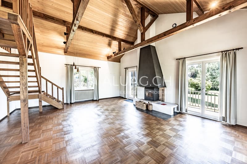 Das Obergeschoss überzeugt mit Parkettboden, sichtbaren Holzbalken und Zugang zum Balkon