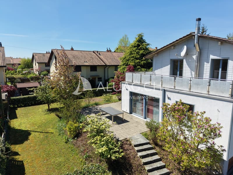 Die Süd-Ost Fassade vom Haus mit dem Anbau aus dem Jahr 2004, dem Sitzplatz und der Gartenanlage.