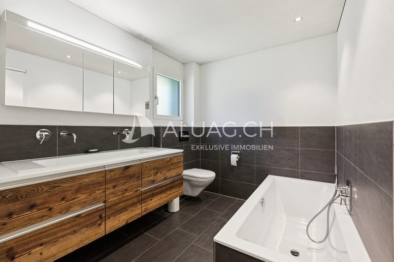 Modernes Badezimmer mit Doppellavabo, Badewanne und warmen Holzakzenten