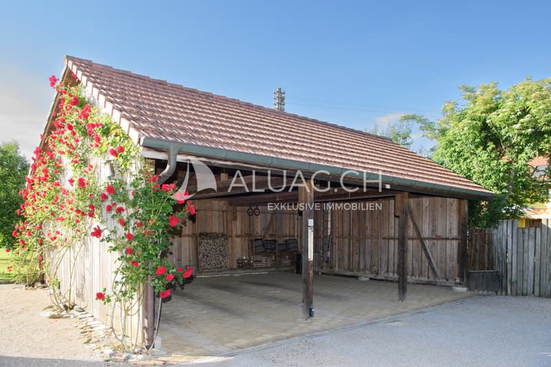 Am Ende vom grossen Vorplatz der Carport mit Ladestation für E-Autos und Platz für drei Fahrzeuge.