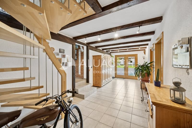 Einladender Eingangsbereich mit stilvollen Holzelementen und sichtbaren Deckenbalken