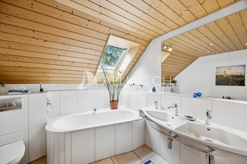 Helles Badezimmer mit Doppelwaschbecken, Badewanne und Dachfenster