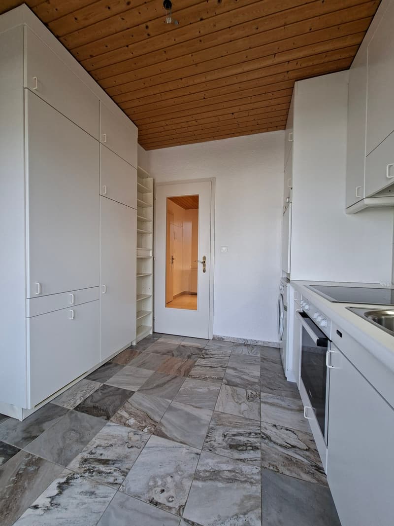 modern kitchen with white cabinets, marble floor, white appliances, wooden ceiling, open door to another room