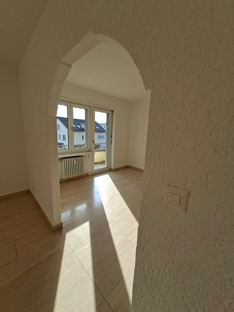 empty room, wooden floor, white walls, arched window, white radiator, sunlight