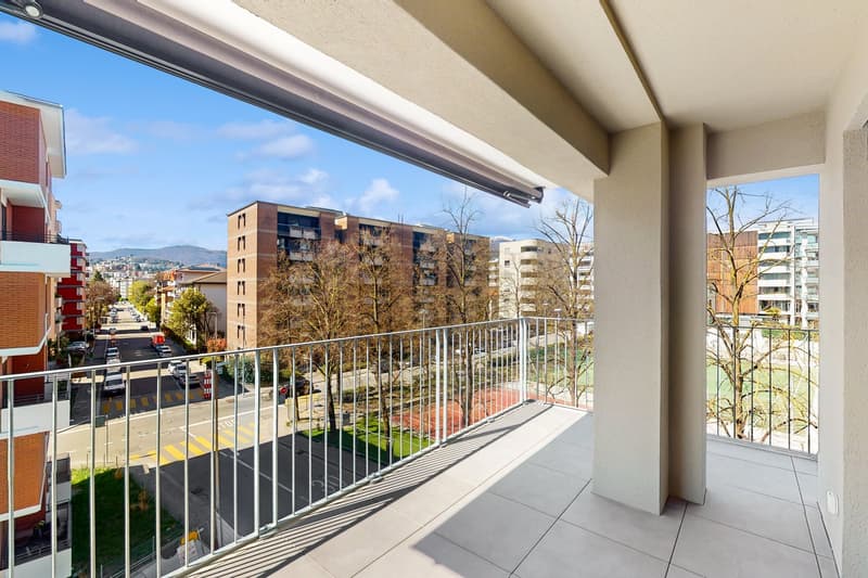 large balcony, metal railing, tiled floor, view of the street and buildings