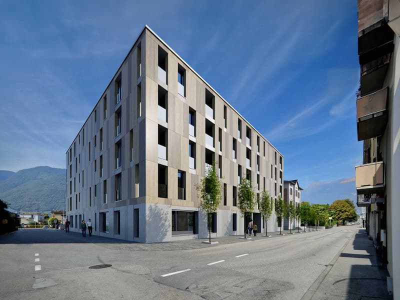 Modern apartment building with multiple floors, concrete and glass exterior, multiple windows, and a flat roof.