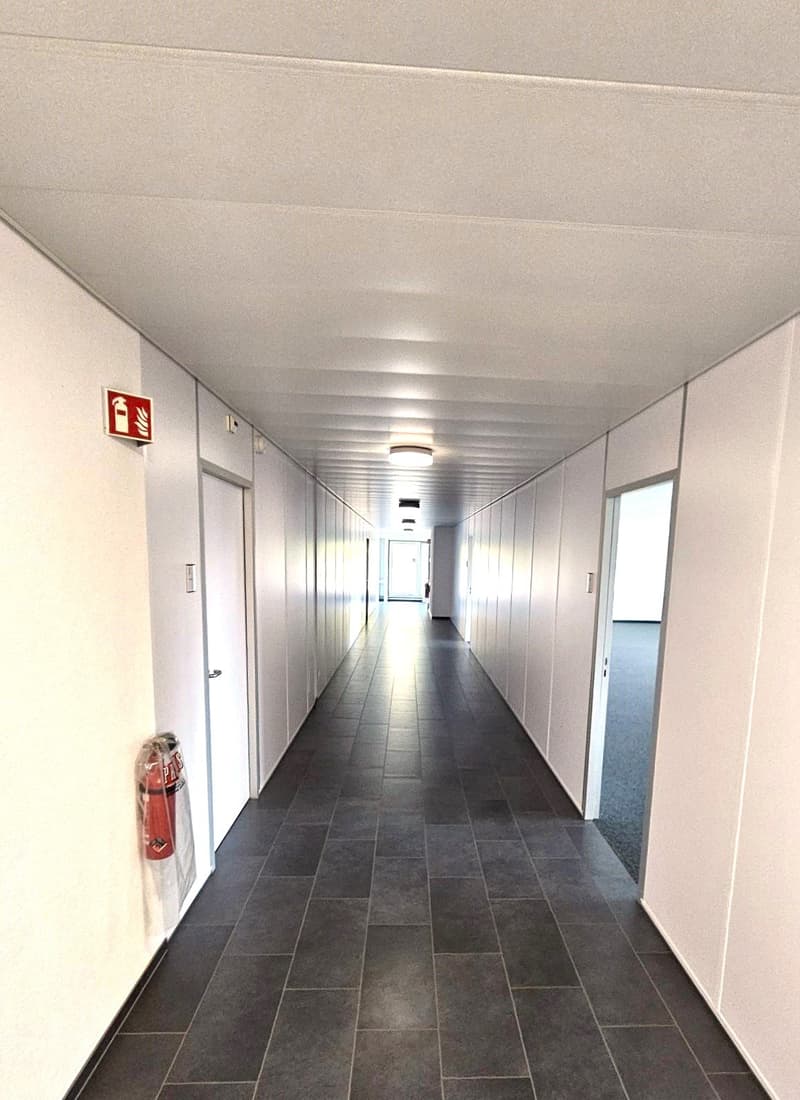 white walls, gray tiles, fire extinguisher, two sets of doors on either side