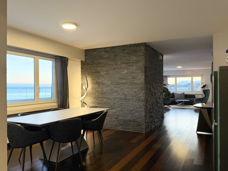 dining area with large window, gray walls, wooden floor, table and chairs, black accent wall