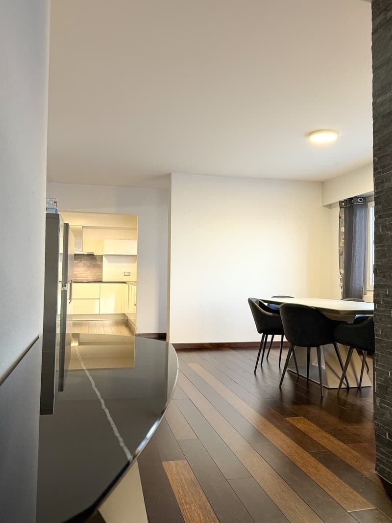modern interior design, white walls, wooden floors, rectangular dining table, black chairs, white built-in fridge, kitchen visible in the background