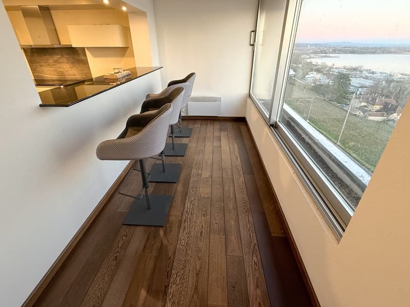 Contemporary styled interior with a bar counter, high windows, and wooden flooring.