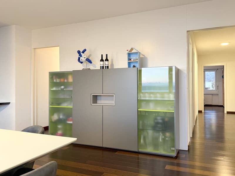 modern style cupboard with glass shelves, wine bottles on top, desk and chair