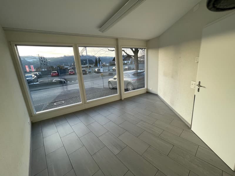 Large windows overlooking street, tiled floor, white walls, single entrance door