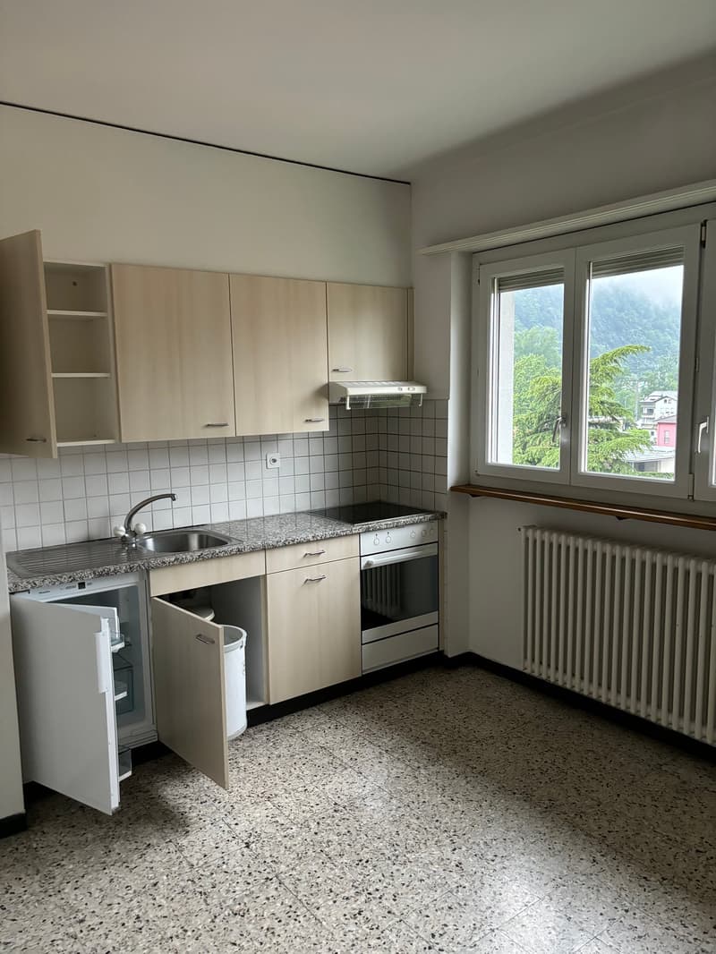 Modern kitchen with wooden cabinets, granite countertop, stainless steel sink, oven, and a window with a view.