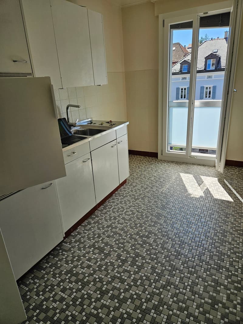 modern kitchen with tile flooring, white cabinets, open sliding door to balcony, stainless steel sink, modern faucet, double glazed windows