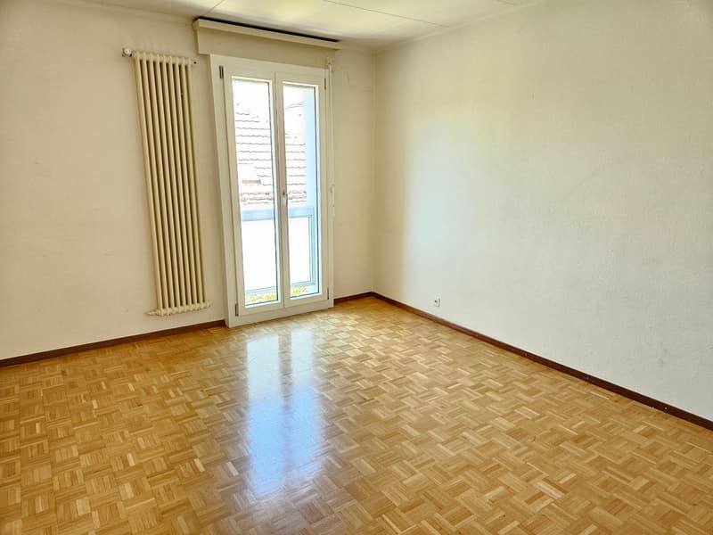 empty room with wooden floor, glass sliding door, and white walls