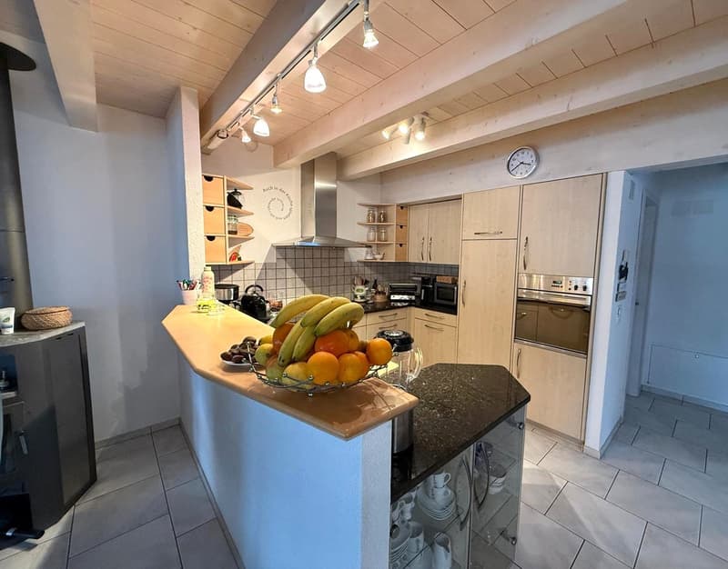 Kitchen with wooden ceiling, island with fruit bowl, wooden cabinets, modern appliances