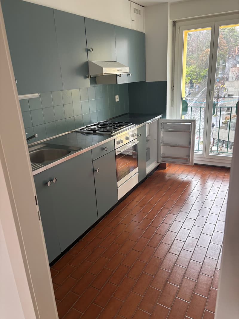 kitchen with blue cabinets, red tiled floor, stainless steel gas stove, oven, refrigerator, sink, balcony with railing