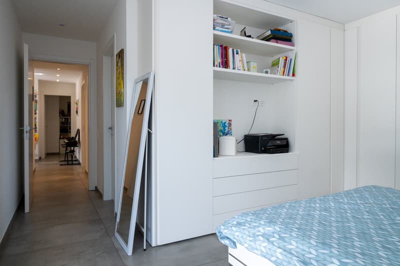 bedroom with bed, white wardrobe, shelves, printer, mirror, wooden floor