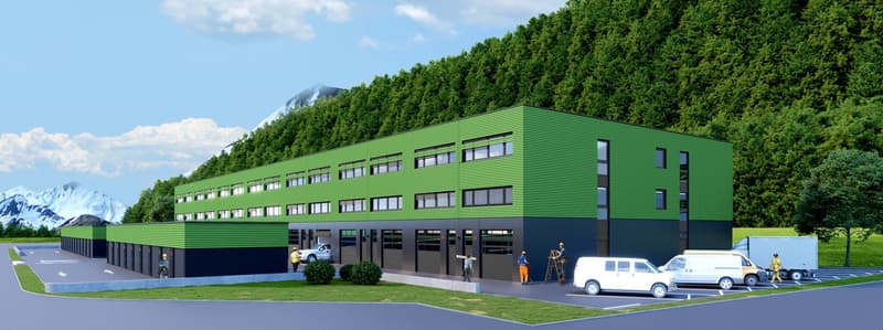 A large green building with a driveway in front of it and several vehicles parked outside.
