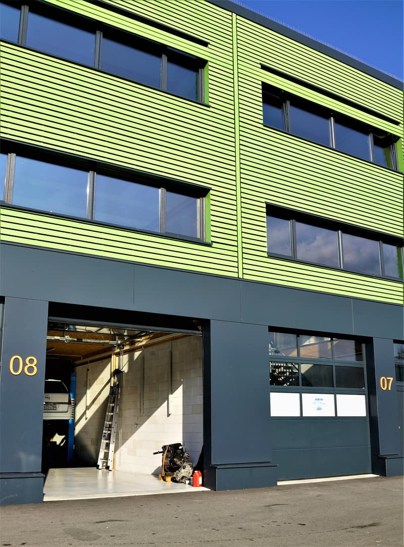 2 story green and gray building, large windows, garage