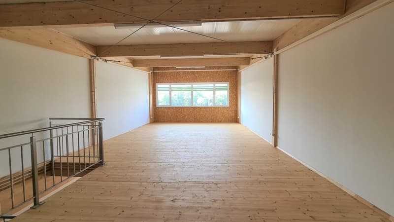 an empty room with wooden floors and a ceiling with visible beams, with a staircase on the left