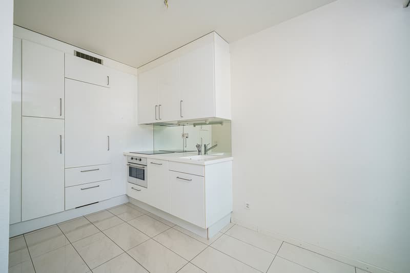 eine leere Küche mit weißen Wänden, weißen Schränken und weißen Geräten / an empty kitchen with white walls and white cupboards and appliances