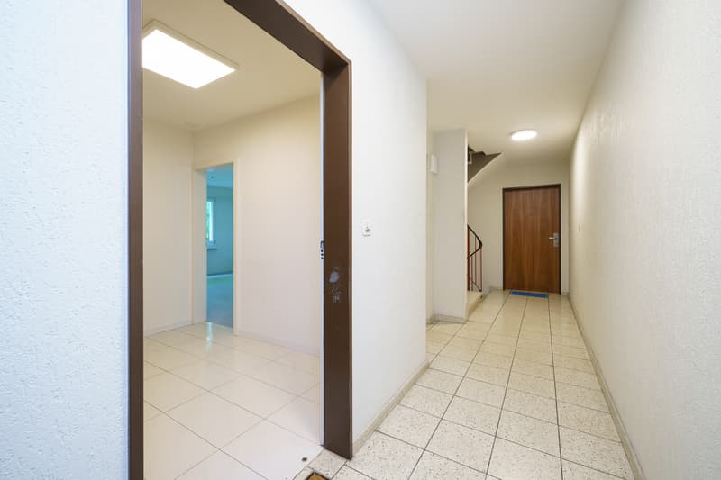 ein leerer Flur mit weißen Wänden und Fliesenboden / an empty hallway with white walls and tiled floors