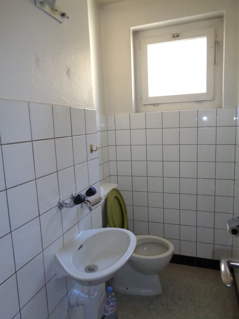 white tiled walls, white sink, white toilet, small window