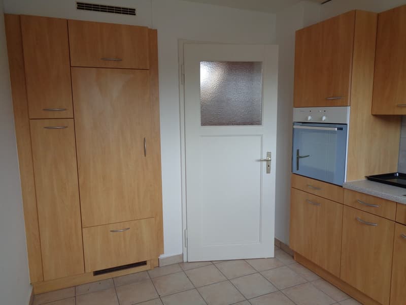 The image shows a kitchen with wooden cabinets, a white door, and a dishwasher visible.