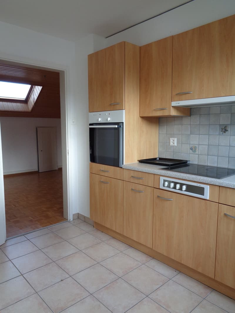 Spacious kitchen with wooden cabinets, built-in oven, and tile flooring. The kitchen has a modern and functional design.