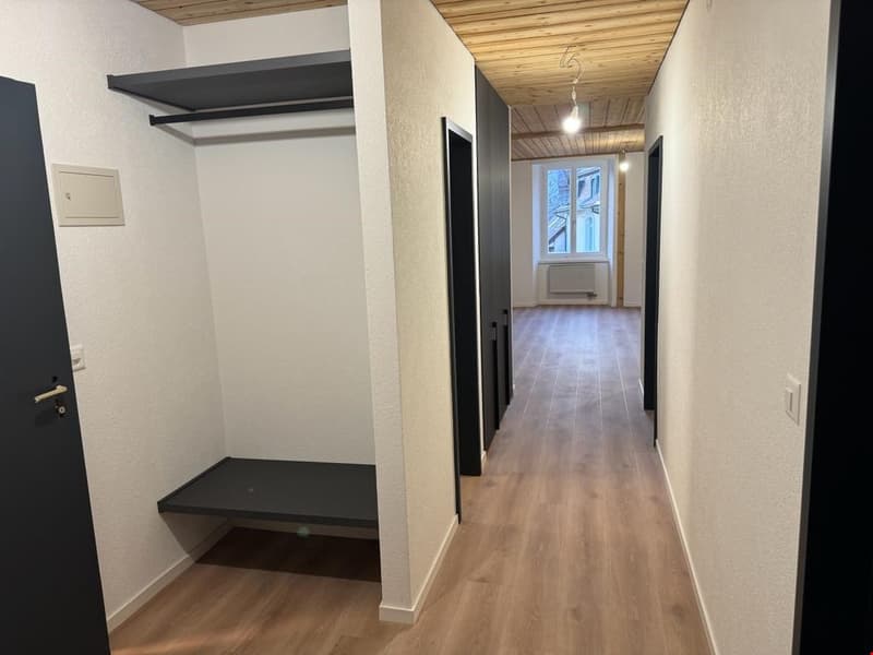 Entryway with closet, open hallway, radiator, hardwood floors, and wooden ceiling