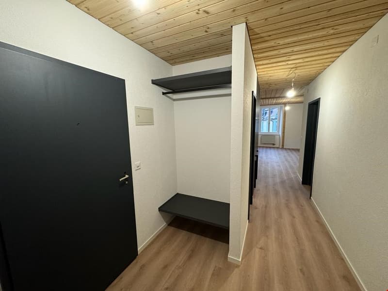 Empty room, white walls, wooden floor, wooden ceiling, wardrobe, bench, and doors